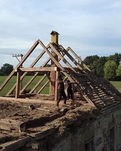 Stodola s odkrytým krovem a dělníky, záběr z dronu