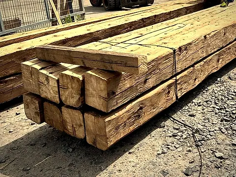Srovnaný stoh starých tesaných trámů stažených páskou
