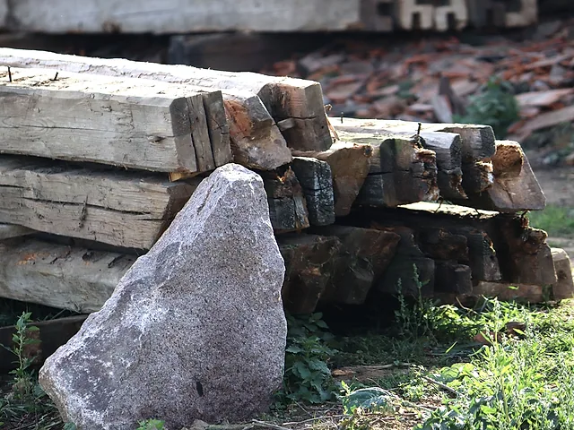 Stoh tesaných trámů u kamene